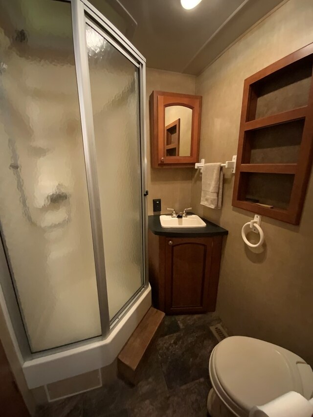 bathroom with vanity, tile patterned floors, a shower with door, and toilet