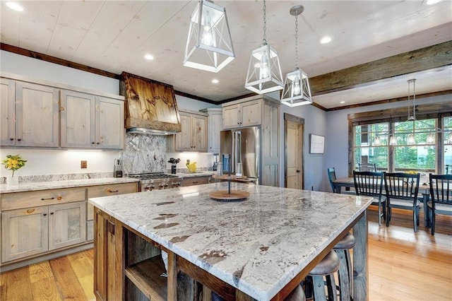 kitchen featuring light stone counters, decorative light fixtures, crown molding, a kitchen island, and high end refrigerator