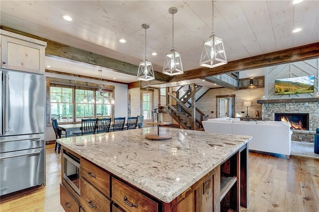 kitchen featuring decorative light fixtures, stainless steel appliances, open floor plan, a kitchen island, and light wood-type flooring