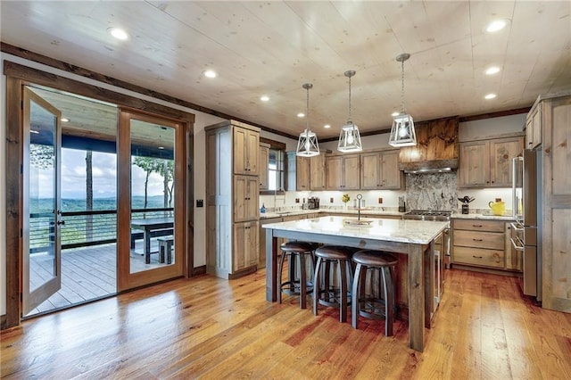 kitchen featuring light wood finished floors, a large island, light stone counters, decorative light fixtures, and premium range hood