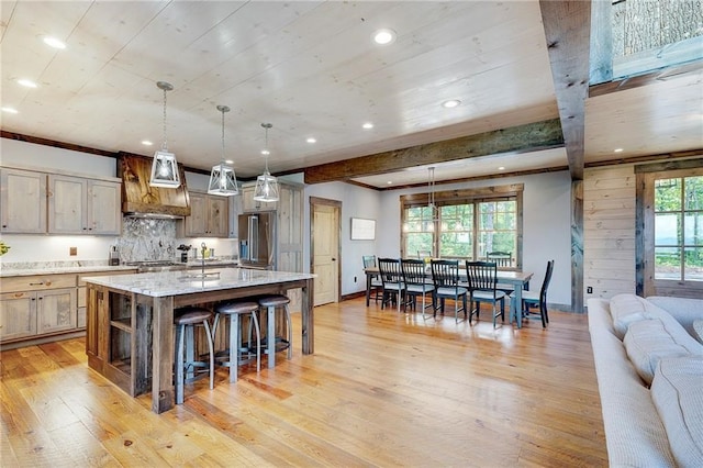 kitchen featuring decorative light fixtures, a large island, a breakfast bar area, light stone countertops, and high end refrigerator