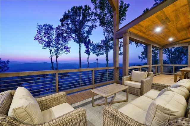 patio terrace at dusk featuring a deck with mountain view and outdoor lounge area