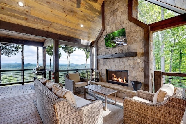 sunroom with vaulted ceiling, an outdoor stone fireplace, and a water and mountain view