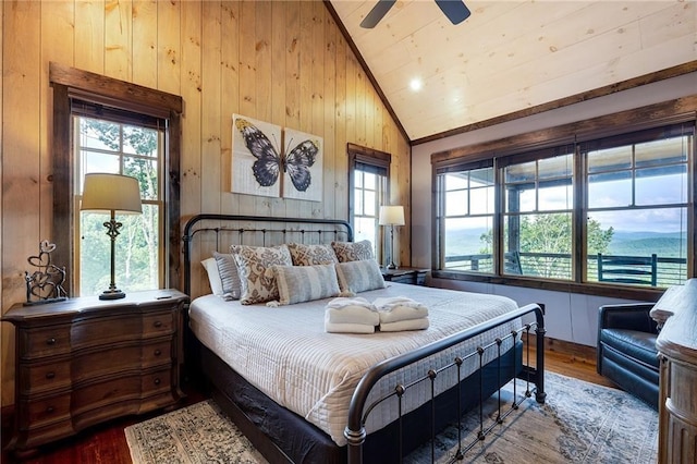 bedroom with high vaulted ceiling, wood walls, wood finished floors, and a ceiling fan