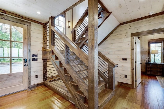 staircase featuring wood finished floors and wooden walls