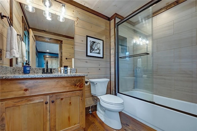 full bath featuring toilet, wood finished floors, combined bath / shower with glass door, vanity, and wood walls