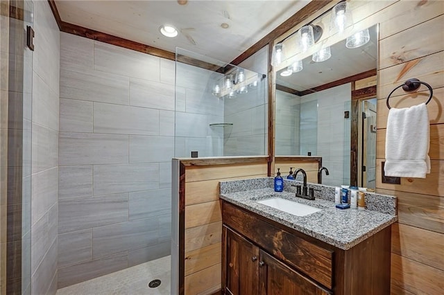 bathroom featuring walk in shower, vanity, and tile walls