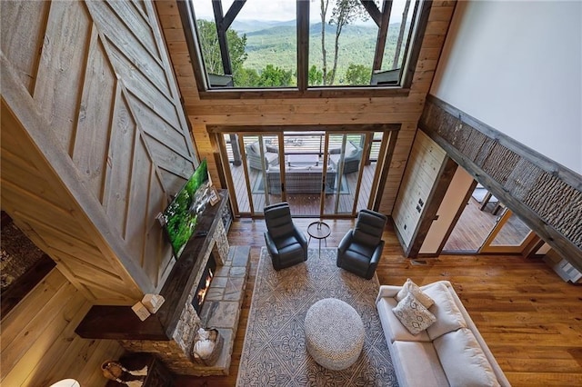 living room featuring wood walls, a towering ceiling, and wood finished floors