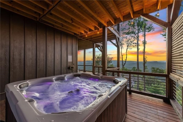 deck at dusk with a water view and a hot tub