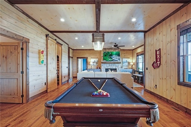 game room with beam ceiling, a fireplace, wood walls, and wood finished floors