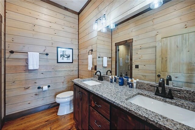 bathroom with wood finished floors, a sink, toilet, and double vanity