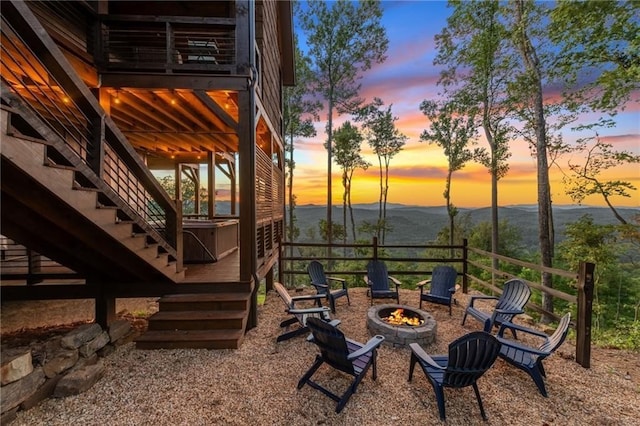 yard at dusk with a deck with mountain view, stairs, and a fire pit