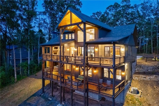 back of property with board and batten siding, a balcony, and central air condition unit