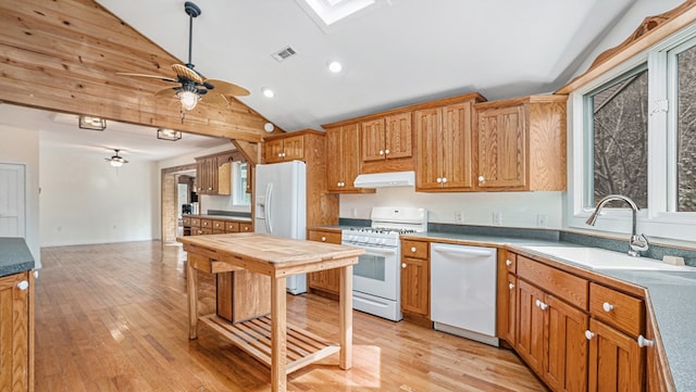 kitchen with white appliances, visible vents, light wood-style flooring, under cabinet range hood, and a sink