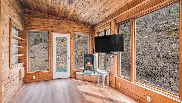 unfurnished sunroom featuring a wood stove, plenty of natural light, wood ceiling, and vaulted ceiling