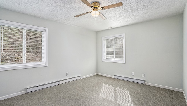 carpeted empty room featuring a healthy amount of sunlight, baseboard heating, and a textured ceiling