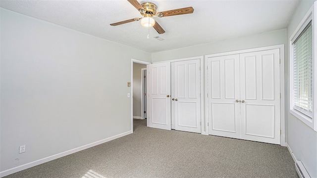 unfurnished bedroom with carpet floors, a baseboard radiator, baseboards, and two closets