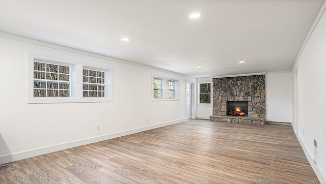 unfurnished living room with a fireplace, recessed lighting, light wood-style floors, ornamental molding, and baseboards