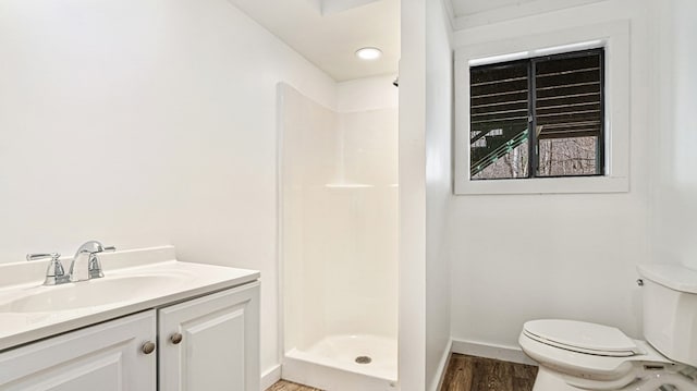 full bath featuring toilet, wood finished floors, vanity, baseboards, and a stall shower