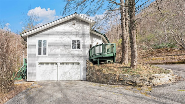 view of side of home with a garage and aphalt driveway