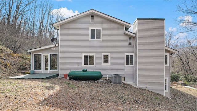 back of property with central AC, a chimney, and heating fuel