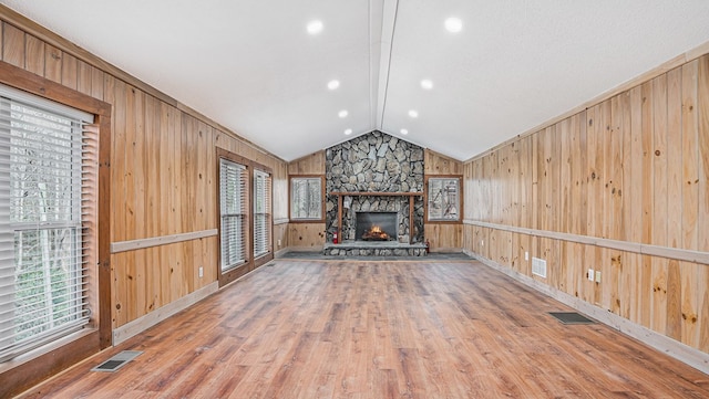 unfurnished living room featuring lofted ceiling, wood walls, and visible vents