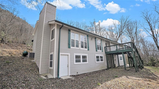 view of side of property featuring a chimney, central AC, stairway, and a wooden deck