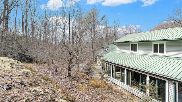 view of side of property featuring a sunroom and metal roof