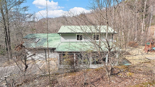 rear view of house featuring metal roof and a forest view