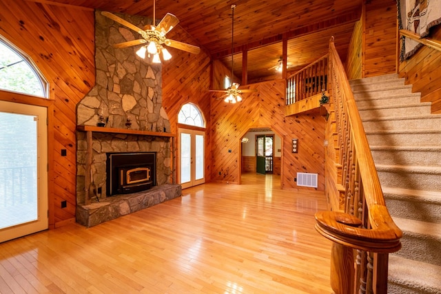 unfurnished living room with light hardwood / wood-style floors, high vaulted ceiling, wooden ceiling, and wood walls