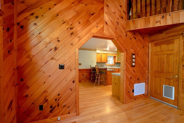 interior space with light hardwood / wood-style floors and wooden walls