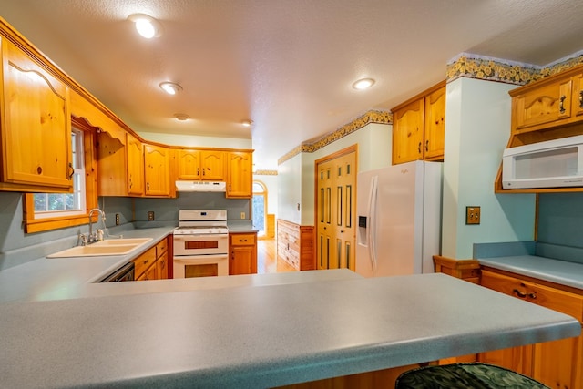 kitchen featuring a textured ceiling, kitchen peninsula, sink, and white appliances