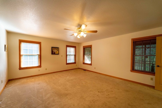 empty room featuring plenty of natural light, ceiling fan, and light colored carpet