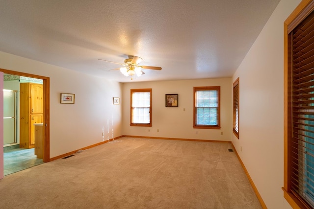 empty room with a textured ceiling, ceiling fan, and light carpet