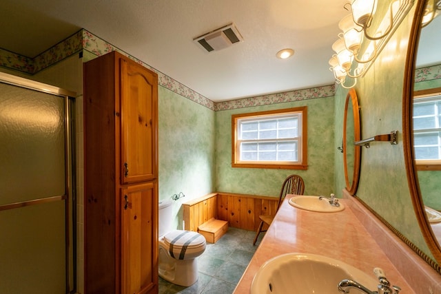 bathroom featuring a healthy amount of sunlight, vanity, toilet, and a shower with shower door