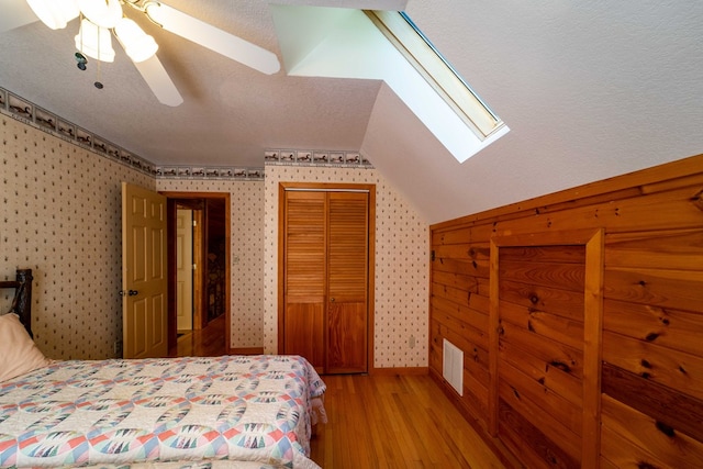 bedroom with ceiling fan, light hardwood / wood-style floors, lofted ceiling, and a closet