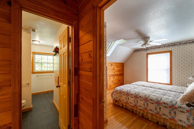 bedroom featuring lofted ceiling, ceiling fan, dark hardwood / wood-style floors, and a textured ceiling