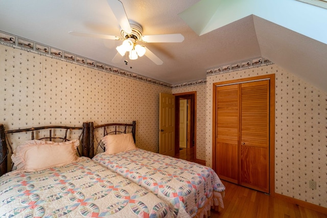 bedroom featuring ceiling fan, a closet, hardwood / wood-style floors, and lofted ceiling