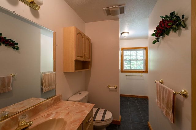 bathroom with vanity, toilet, and a textured ceiling