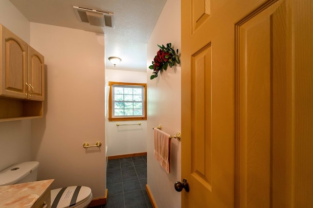 bathroom featuring a textured ceiling, vanity, and toilet