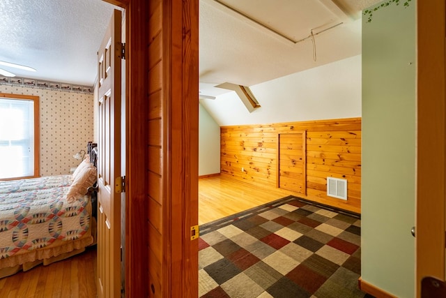 bonus room featuring a textured ceiling and wooden walls