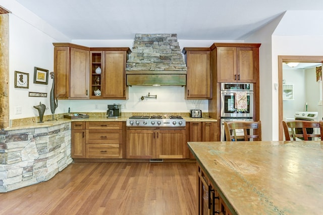 kitchen with appliances with stainless steel finishes and light hardwood / wood-style flooring