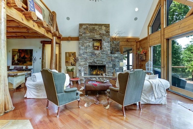 living room with a healthy amount of sunlight, light hardwood / wood-style floors, a fireplace, and high vaulted ceiling