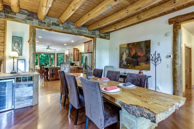 dining space featuring hardwood / wood-style flooring, beam ceiling, wooden ceiling, bar area, and ceiling fan