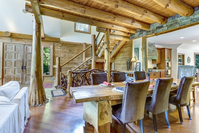 dining space featuring light hardwood / wood-style flooring, beamed ceiling, wooden ceiling, and wooden walls