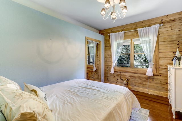 bedroom featuring a closet, a notable chandelier, hardwood / wood-style flooring, and wooden walls