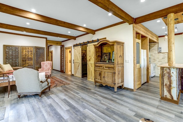 living room featuring a barn door, beamed ceiling, and wood-type flooring