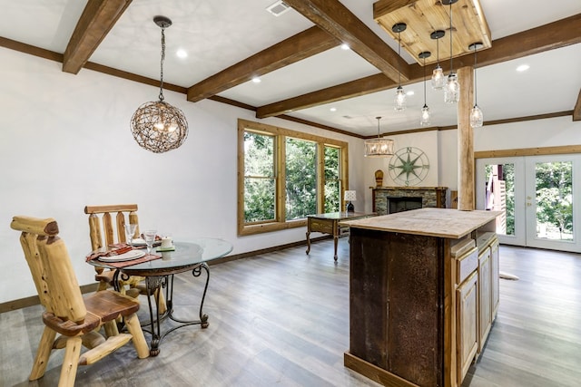 kitchen featuring a stone fireplace, light wood-type flooring, a kitchen island, and hanging light fixtures