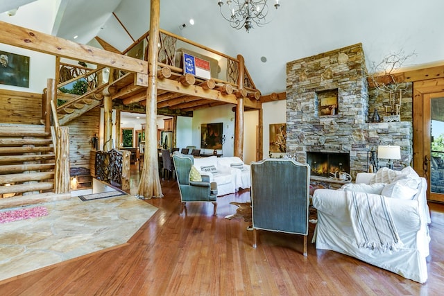 living room featuring log walls, high vaulted ceiling, wood-type flooring, and a stone fireplace