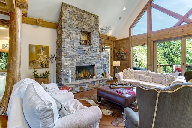 living room with a stone fireplace, high vaulted ceiling, wood-type flooring, and beamed ceiling